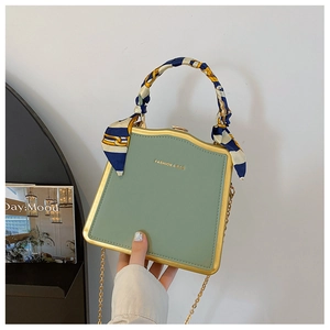 Dettaglio borsa quadrata verde menta con cornice dorata e foulard decorativo sul manico