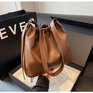 Detailed shot of brown leather shoulder bag with drawstring closure in elegant packaging