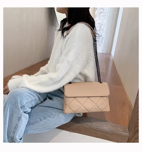 Detail shot of the beige quilted chain bag texture and soft leather finish on model