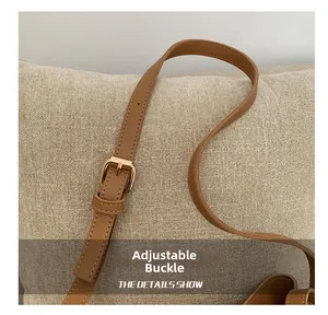 Detail showing adjustable golden buckle and premium stitching on brown leather bag strap