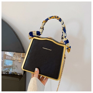 Dettaglio della borsa a scatola nera con cornice dorata e foulard sulla maniglia