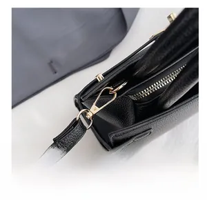 Detail of high-gloss gold metal hooks and D-ring on black lychee grain leather tote