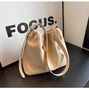 Detail of beige soft leather bucket bag featuring a drawstring closure and logo detail