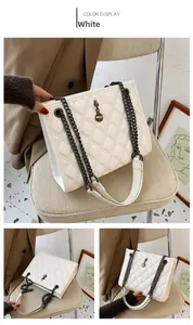 Detail of white quilted handbag with black chunky chain and round metal pendant