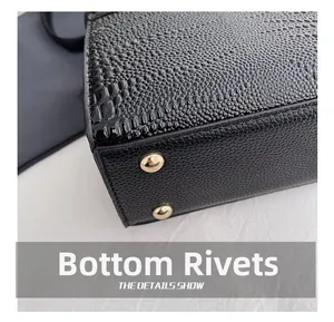 Close-up of black crocodile embossed leather handbag with protective gold metal rivets