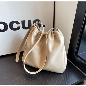 Close-up of beige soft leather underarm bag with pleated texture and adjustable strap
