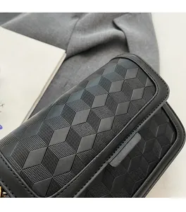 Detail of black crossbody bag featuring unique 3D geometric embossed pattern and texture