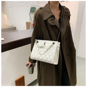 Detail view of quilted white chain bag worn with a stylish trench coat for women