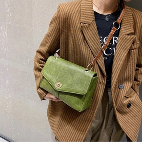 Detailed view of vintage green crossbody bag with gold round lock and brown leather strap