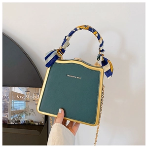 Dettaglio della clutch rigida verde scuro con cornice dorata e manico in seta