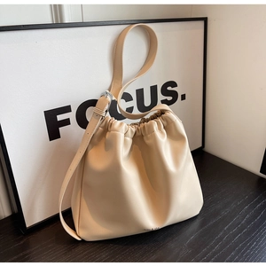 Detail view of cream drawstring handbag with miao & sha logo on a sleek black surface