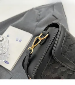 Detail shot of black crossbody bag side with gold hardware and geometric textured leather