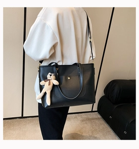 Detail of black large capacity tote bag featuring magnetic snap pocket and plush bear charm