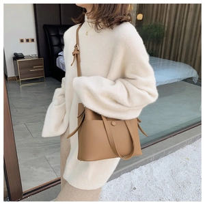 Fashionable camel bucket bag styled with a white oversized sweater in a cozy setting