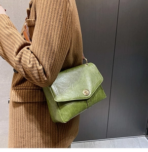 Detail of vintage dark green crossbody bag with gold twist lock on striped blazer
