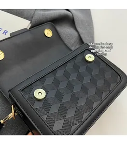 Close-up of black crossbody bag with 3D geometric texture and dual gold magnetic buckles