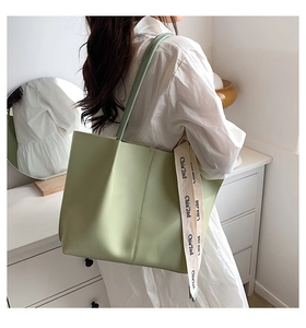 Detail of light green tote bag featuring decorative ribbon and vertical stitching accents