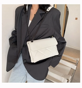 Detail of white quilted chain bag with elegant diamond pattern and metal strap