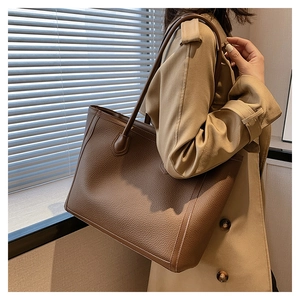 Detail of the large brown tote bag showing pebbled leather texture on a female model