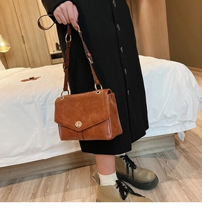 Detailed side view of vintage brown crossbody bag with gold metal lock and oil-wax texture