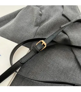 Detail of adjustable black leather shoulder strap with gold-tone buckle on crossbody bag