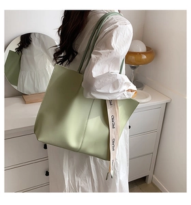 Detail of mint green tote bag featuring a branded white canvas shoulder strap strap in a room