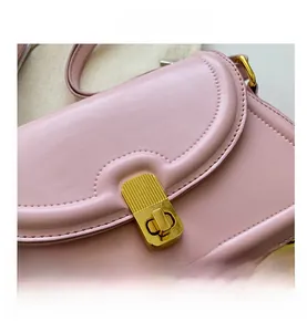 Close-up of pink leather handbag with scalloped flap and gold textured swivel lock