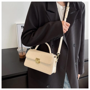 Detail of beige faux crocodile skin texture and gold clasp on a crossbody bag