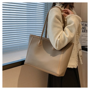Detail of beige lychee pattern tote bag with long handles and vertical decorative straps
