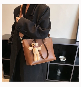 Brown leather tote bag on model showing large capacity and adjustable strap detail