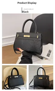 Detail of black crocodile texture handbag with golden swivel lock and shoulder strap