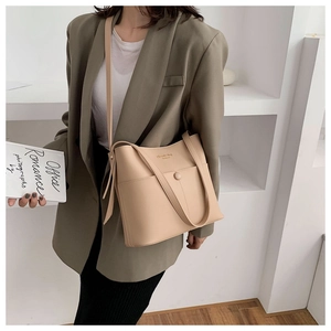 Detail view of a beige minimalist bucket bag featuring a front pocket with snap button