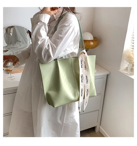 Detail of light green tote bag with ribbon decoration and large interior capacity