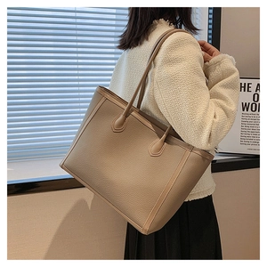 Litchi pattern leather tote bag in khaki finish shown on shoulder for daily commute style
