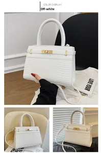 Detail of off-white crocodile embossed tote bag with gold hardware and top handle strap