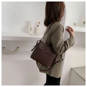 Detail of dark brown matte leather bucket bag with gold Classic Bag embossing