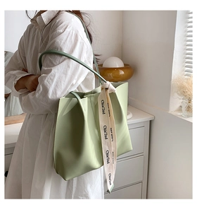 Detail of light green tote bag with white canvas ribbon and matte leather texture