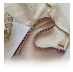 Close-up of pink leather saddle bag with adjustable strap and golden hardware accents
