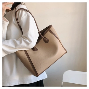 Detail view of the pebbled leather texture and reinforced brown straps on a tan tote bag