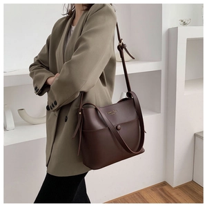 Detail of dark brown leather bucket bag with Classic Bag gold embossing and adjustable strap