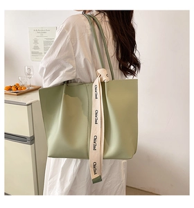 Detail of light green large capacity tote bag with decorative lettered webbing strap