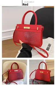 Detail of red crocodile texture handbag with golden hardware and detachable strap