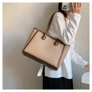 Detail of a large two-tone tote bag with beige textured leather and brown straps