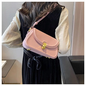Detail of pink baguette bag with gold buckle on a model wearing a black velvet dress