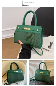 Detail view of green crocodile texture tote bag with golden metal lock and strap