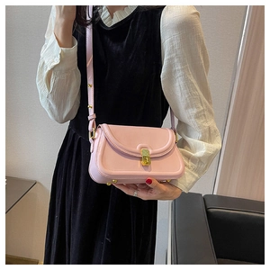 Detail of light pink crossbody bag with gold hardware and adjustable studded strap