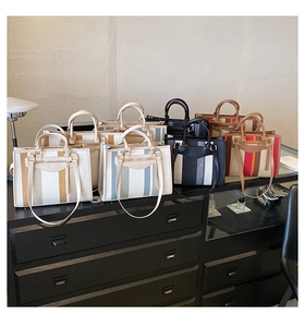 Detailed close-up of striped canvas tote bags in various colors on a black display counter