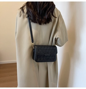 Close-up of black crossbody bag with 3D cube embossed texture and gold metal buckle