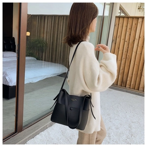 Black matte leather bucket bag with gold lettering shown from a stylish side view profile