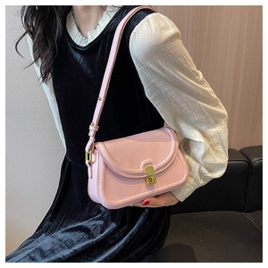 Detailed view of pink leather small square bag with gold metal buckle and thin shoulder strap